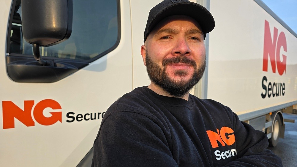 Mannlig sjåfør for NG Secure i uniform foran transportbil med NG Secure-logo.